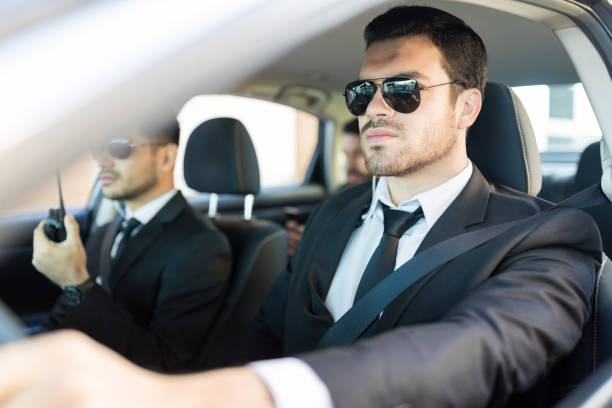 Confident secret service agent wearing sunglasses while driving car in city